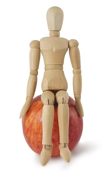 stock image The wooden mannequin sits on a ripe apple