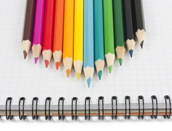 Многоцветные карандаши на спиральном блокноте — стоковое фото