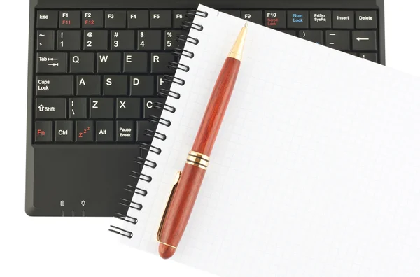Ручка и спиральный блокнот на клавиатуре ноутбука — стоковое фото