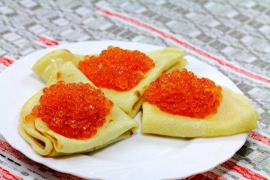 Three appetizing pancakes with soft caviar on the plate