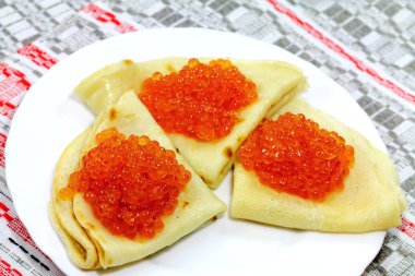 Three tasty pancakes with soft caviar on the white plate