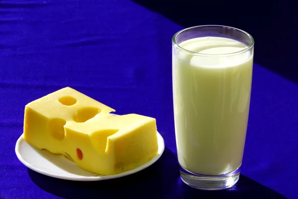 Un vaso de leche y un trozo de sabroso queso — Foto de Stock