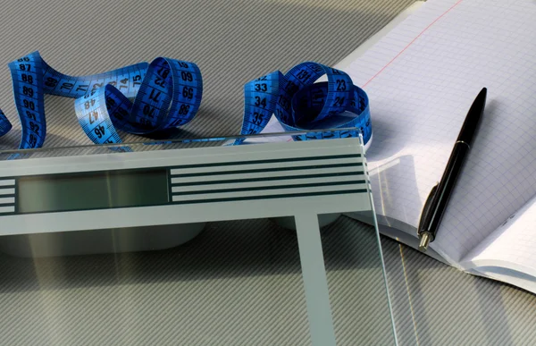 Váhy, metr opatření pravítko, tužku a zápisník na stůl — Stock fotografie