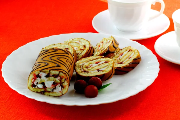 Swiss roll and three cherries on the white plate — Stock Photo, Image