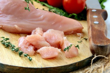 Raw sliced chicken on a wooden board clipart