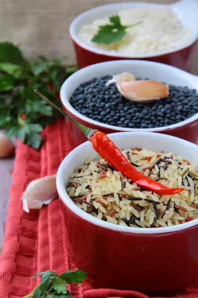 Kommen van ongekookte rijst en chilipepers — Stockfoto