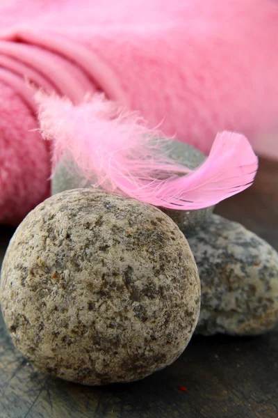 Taşlar ve arka planda pembe havlu üzerinde pembe tüy — Stok fotoğraf