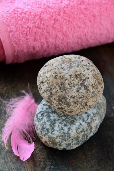 粉红色的羽毛上的石块和背景水疗概念中的粉红色毛巾 — 图库照片