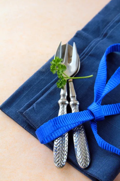 Lžíce a vidlička v modrý ubrousek s petrželkou — Stock fotografie