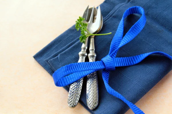 Lžíce a vidlička v modrý ubrousek s petrželkou — Stock fotografie