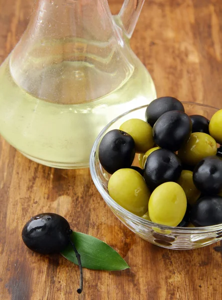 Zwarte en groene olijven en een fles olijfolie — Stockfoto