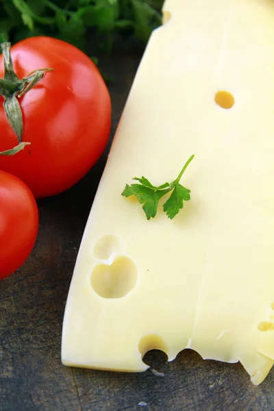 Gran pedazo de variedades de queso Maasdam y tomate —  Fotos de Stock