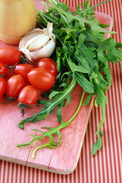 Bunch of fresh arugula with garlic and tomato — Stock Photo, Image