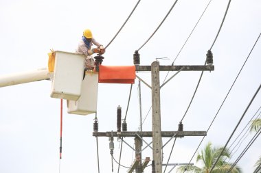Electrician stays on the tower pole and repairs a wire of the power line clipart