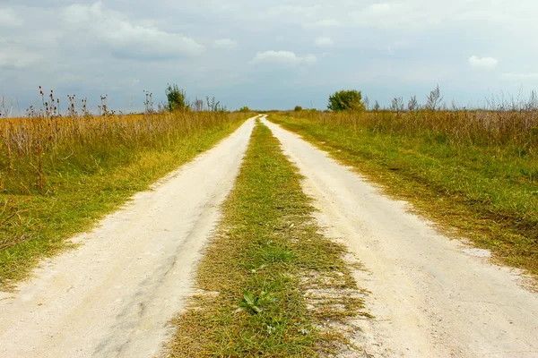 Rural bedekt met witte zandsteen weg tussen velden — Stockfoto