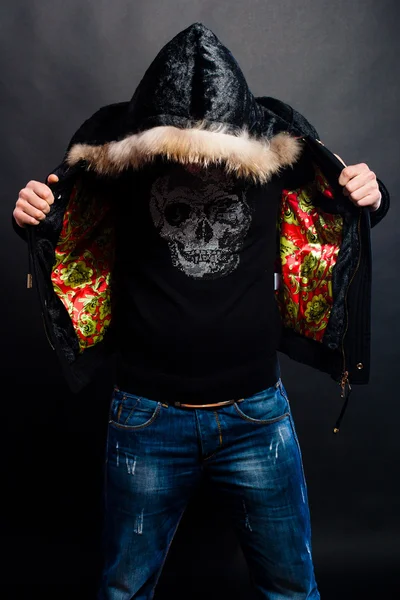 Man op een zwarte achtergrond in een jas met een kap met zijn hoofd naar beneden Stockfoto