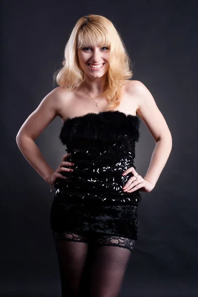 Piękny blond model w czarnej sukni, pozowanie na czarnym tle — Zdjęcie stockowe