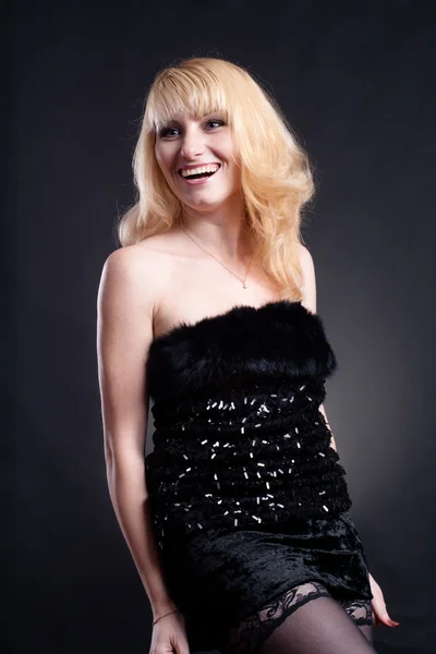 Beautiful blond model in black dress posing on black background — Stock Photo, Image