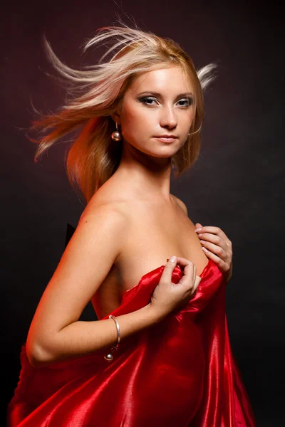 Belle blonde en studio sur fond noir avec tissu rouge — Photo