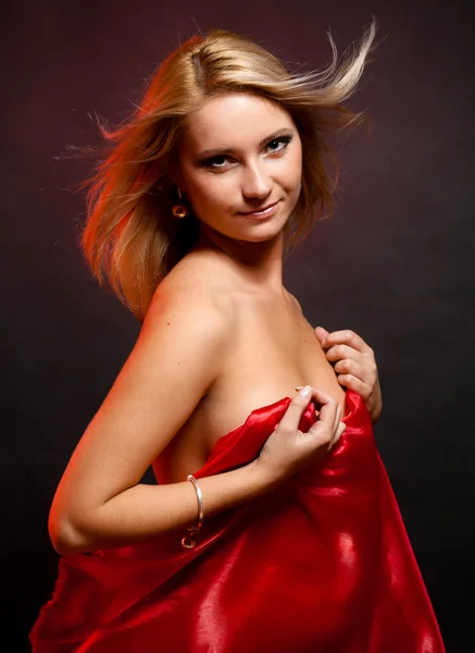 Bela loira no estúdio em um fundo preto com pano vermelho — Fotografia de Stock