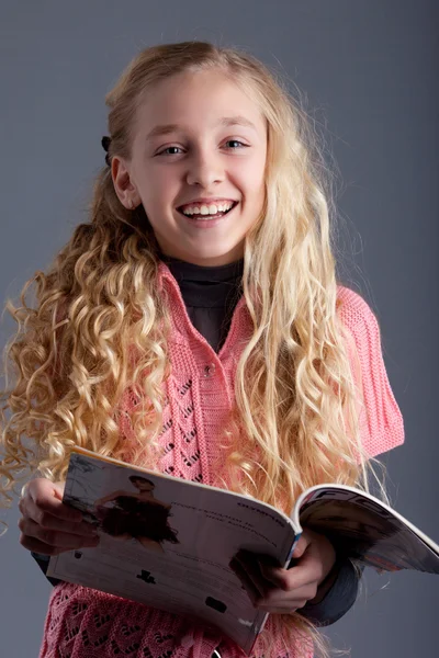 Studio portrait of a blonde girl with a magazine — Stock Photo, Image