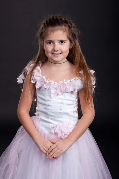 Μικρό κορίτσι μελαχρινή σε ένα ελαφρύ φόρεμα σε μαύρο φόντο — Φωτογραφία Αρχείου
