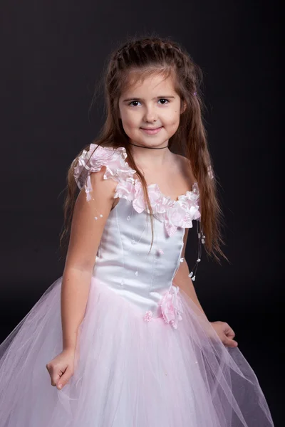 Kleines Mädchen brünett in einem hellen Kleid auf schwarzem Hintergrund — Stockfoto
