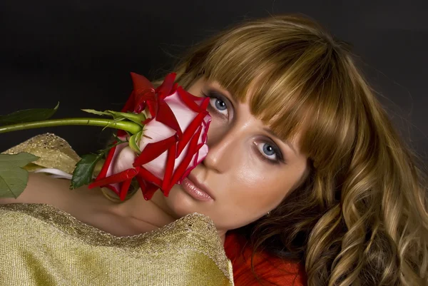 Красивая девушка с красным цветком смотрит на тебя, фокусируясь на глазах — стоковое фото
