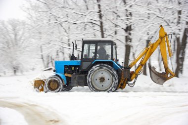 Tractor removes snow in a park clipart