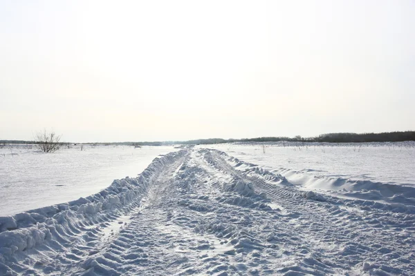 stock image Snow covered road in winter with mountains in the distance