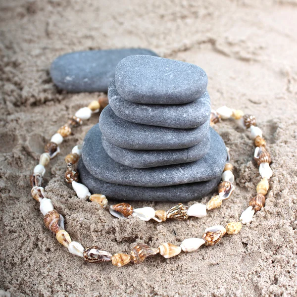圆蓝石头躺在沙里 所作的贝壳珠 — 图库照片