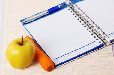 açık defter, sarı elma ve kalem