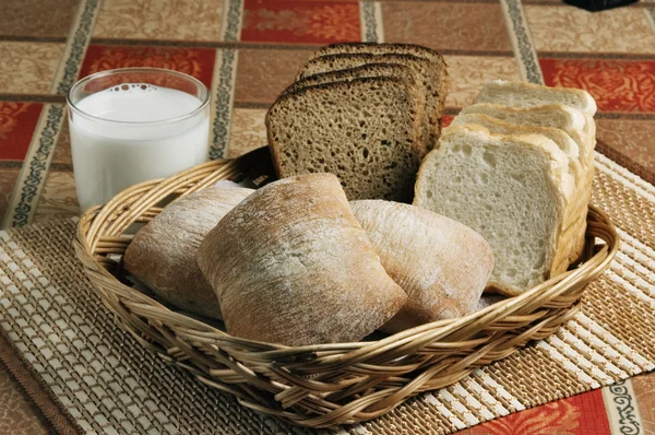 Pan y un vaso de leche en una canasta sobre una mesa — Foto de Stock