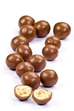 Dark brown chocolate balls and half with crisp filling over white background clipart