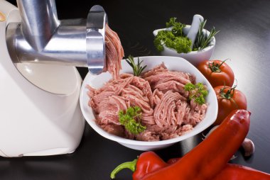 Bowl of mince with electric meat grinder and vegetables clipart