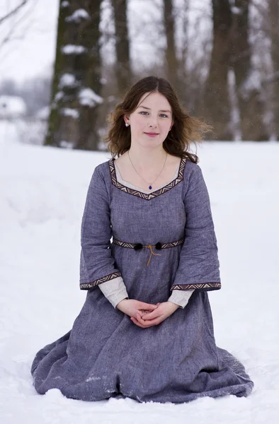 Dívka ve středověkých šatech sedět ve sněhu — Stock fotografie