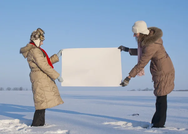 Niñas sosteniendo cartel blanco en el campo de nieve de invierno — Foto de Stock