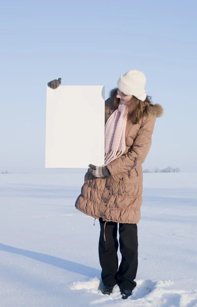Девушка с белым плакатом на зимнем снежном поле — стоковое фото