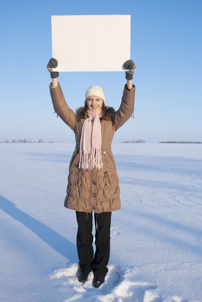 Dívka drží bílý plakát na zimní zasněžené pole — Stock fotografie