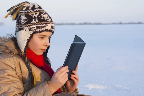 Teen girl reading e-book outdoors at winter time — Stock Photo, Image