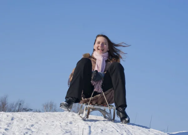 Chica adolescente en trineo desde una colina — Foto de Stock