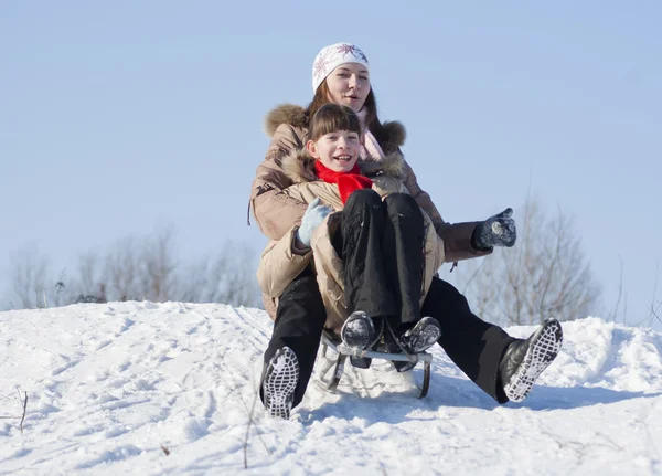 Two happy sisters sledding at winter time — Stock Photo, Image
