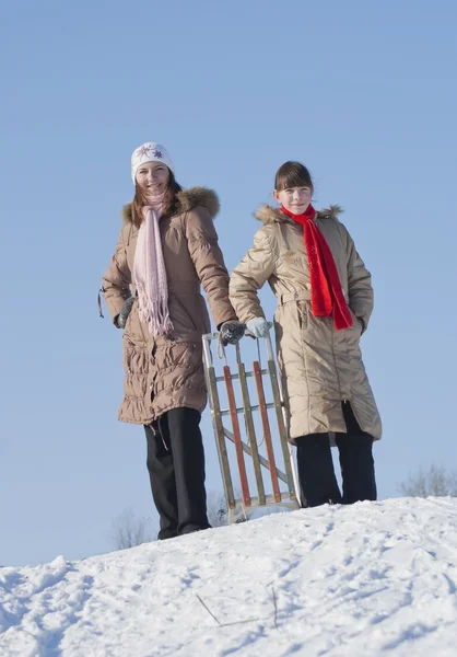 雪橇在冬季时的两个快乐姐妹 — 图库照片