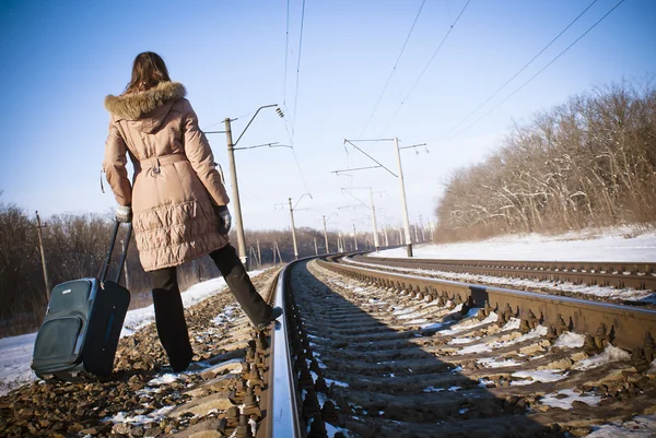 Tiener meisje met een koffer in de buurt van de spoorwegen in de wintertijd — Stockfoto