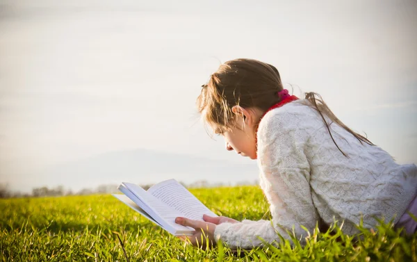 草の上の本を読んでいる女の子 — ストック写真