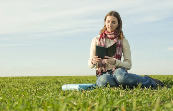 Meisje het lezen van een ebook zittend op gras — Stockfoto