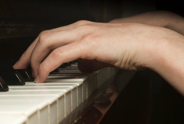 Child's hand playing on piano keyboard clipart