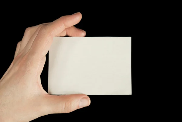Mão segurando um cartão branco isolado no fundo preto — Fotografia de Stock