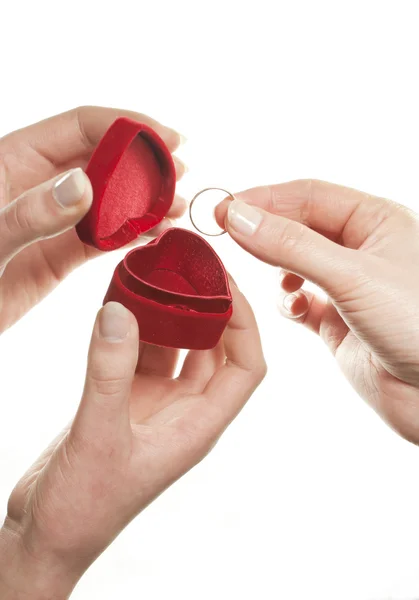 Mãos com uma caixa em forma de coração e um anel sobre fundo branco — Fotografia de Stock