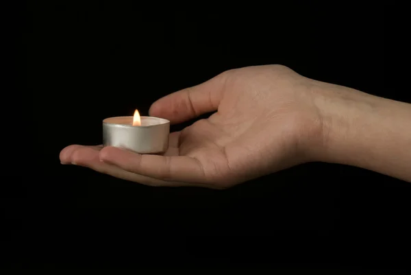 Hand holding a candle on black background